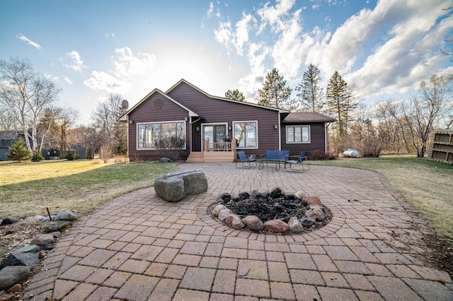 back of property featuring a fire pit, a yard, and a patio