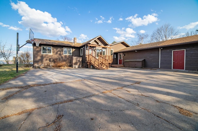 ranch-style home featuring a storage shed, a chimney, concrete driveway, and an outdoor structure