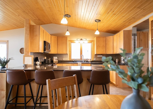 kitchen with stainless steel appliances, backsplash, dark countertops, vaulted ceiling, and a peninsula