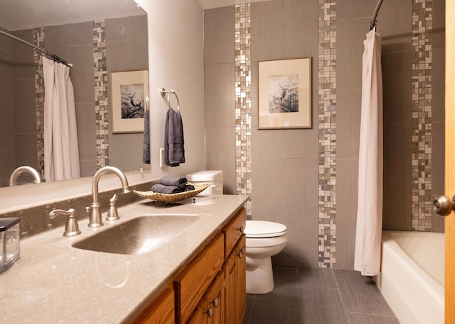 full bath featuring tile patterned floors, toilet, tile walls, shower / bath combo with shower curtain, and vanity