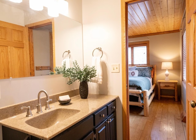 ensuite bathroom featuring ensuite bathroom, wood ceiling, hardwood / wood-style flooring, vanity, and ornamental molding