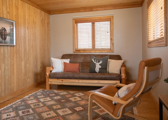 sitting room featuring wood ceiling, baseboards, wood walls, and ornamental molding