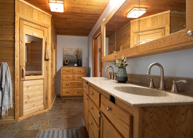 bathroom featuring stone tile flooring, double vanity, wood ceiling, and a sink