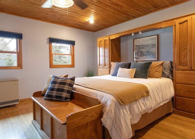 bedroom with wooden ceiling, radiator heating unit, multiple windows, and light wood-style flooring