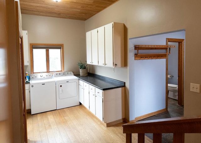laundry area featuring wood ceiling, independent washer and dryer, light wood-style floors, and cabinet space