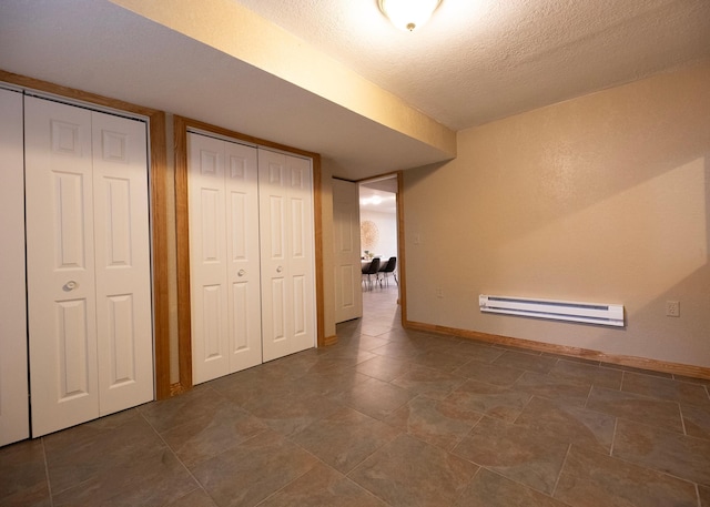 unfurnished bedroom with a baseboard heating unit, multiple closets, baseboards, and a textured ceiling