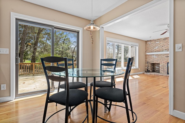 1337 Kenilworth Dr, Woodbury, MN 55125 - dining room featuring a brick fireplace, ceiling fan, plenty of natural light, and light wood-type flooring