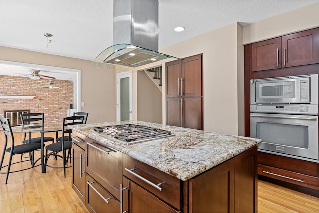 1337 Kenilworth Dr, Woodbury, MN 55125 - kitchen with light stone countertops, appliances with stainless steel finishes, light wood-style flooring, a center island, and island exhaust hood