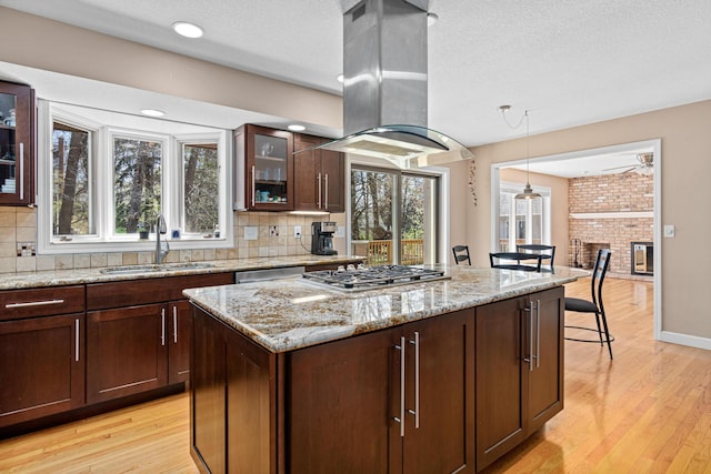 1337 Kenilworth Dr, Woodbury, MN 55125 - kitchen featuring appliances with stainless steel finishes, a sink, light wood-style flooring, decorative backsplash, and island exhaust hood