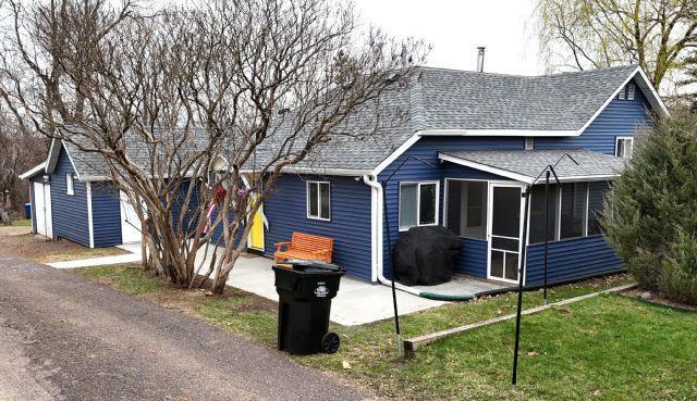 21 Main St, Luck, WI 54853 - view of front of property featuring a shingled roof, a sunroom, and a front lawn