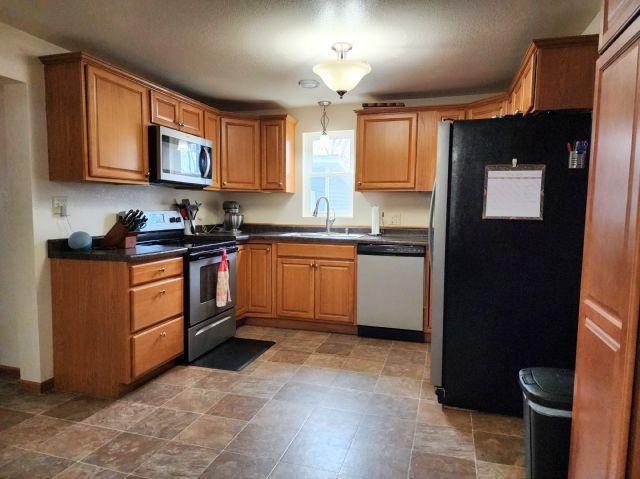 21 Main St, Luck, WI 54853 - kitchen with appliances with stainless steel finishes, dark countertops, and brown cabinetry