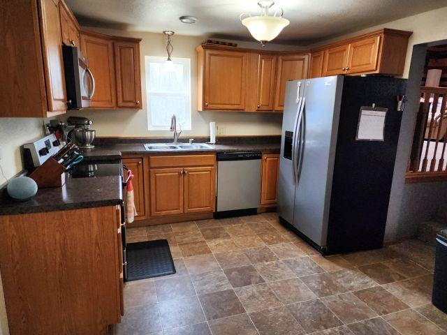 21 Main St, Luck, WI 54853 - kitchen with stainless steel appliances, dark countertops, brown cabinets, pendant lighting, and stone finish flooring