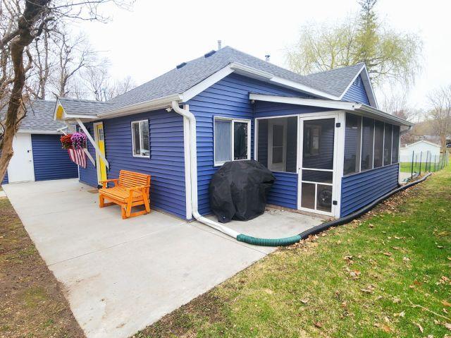 21 Main St, Luck, WI 54853 - rear view of property featuring a sunroom, roof with shingles, a patio, and a lawn
