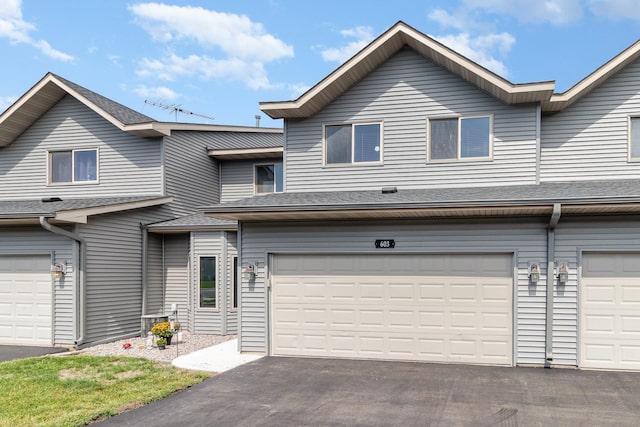 multi unit property with a shingled roof, aphalt driveway, and a garage
