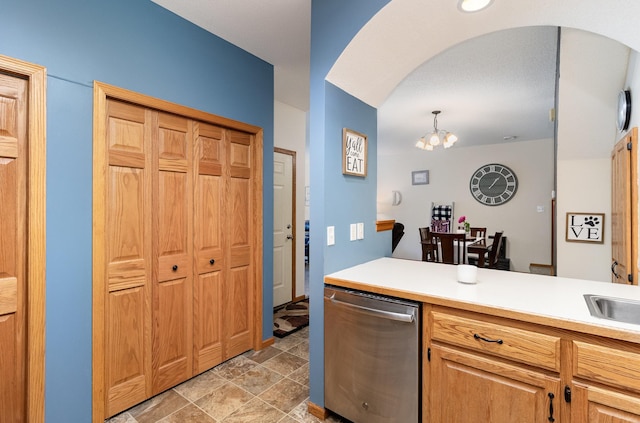 kitchen with arched walkways, stainless steel dishwasher, a notable chandelier, and light countertops