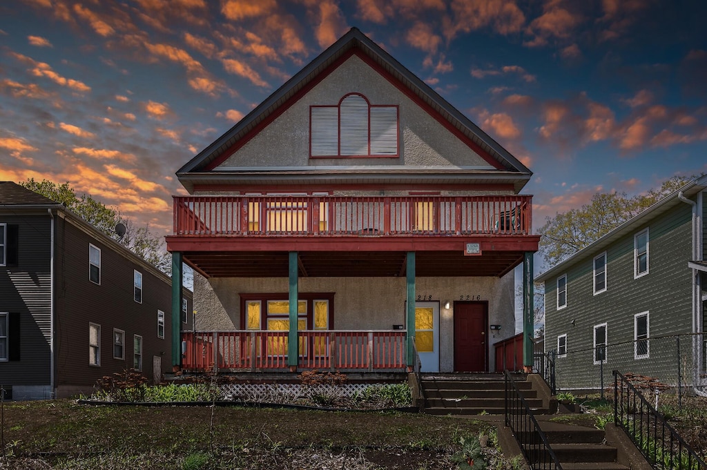 back of property with a porch and stucco siding