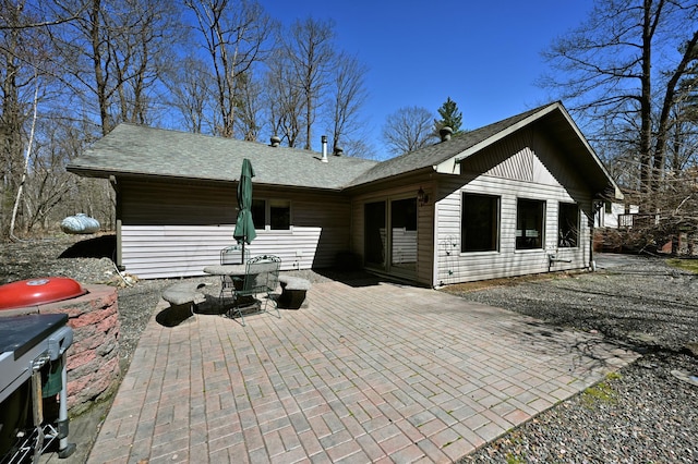 back of house featuring a patio and roof with shingles