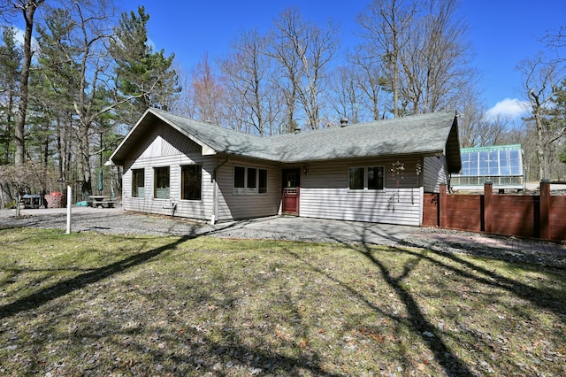 rear view of property featuring a patio, a yard, a shingled roof, and fence