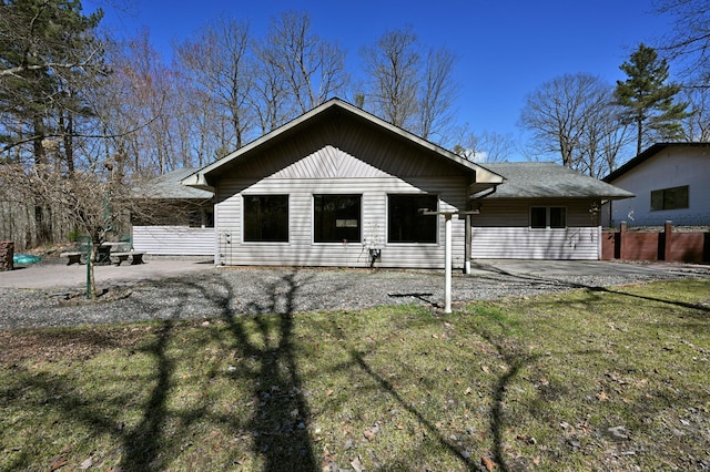 view of front facade with fence, roof with shingles, a patio area, and a front yard