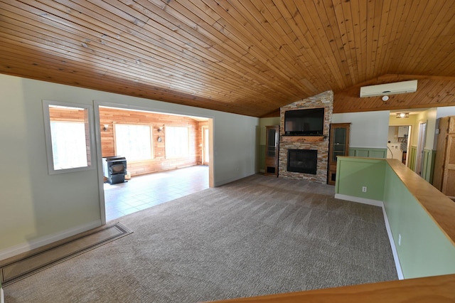 unfurnished living room featuring wood ceiling, carpet flooring, a wood stove, a wall mounted AC, and vaulted ceiling