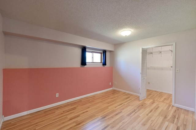 unfurnished bedroom with baseboards, wood finished floors, a textured ceiling, and a closet