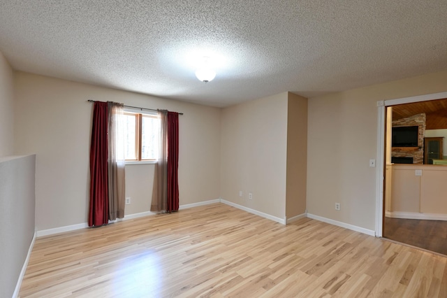 unfurnished room featuring a textured ceiling, light wood-style flooring, and baseboards