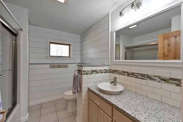 bathroom with tile patterned floors, an enclosed shower, toilet, vanity, and a textured ceiling