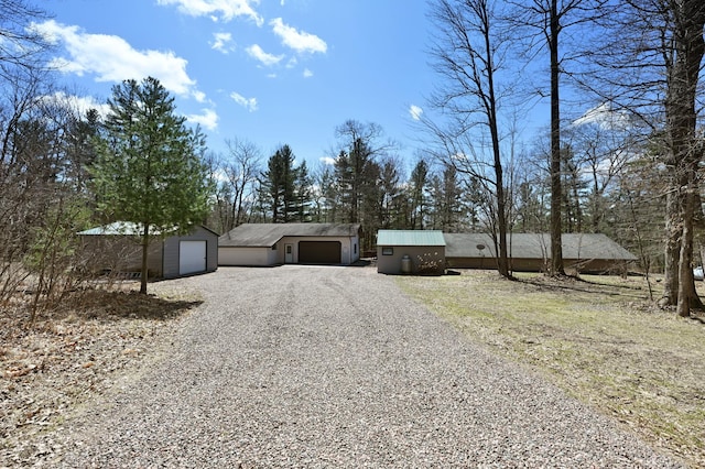 view of front of property with a detached garage, gravel driveway, and an outbuilding