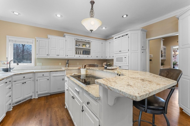 kitchen with a sink, white cabinetry, a kitchen island, and white appliances