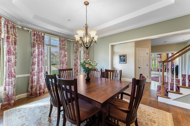 dining room with a notable chandelier, stairs, baseboards, wood finished floors, and a tray ceiling