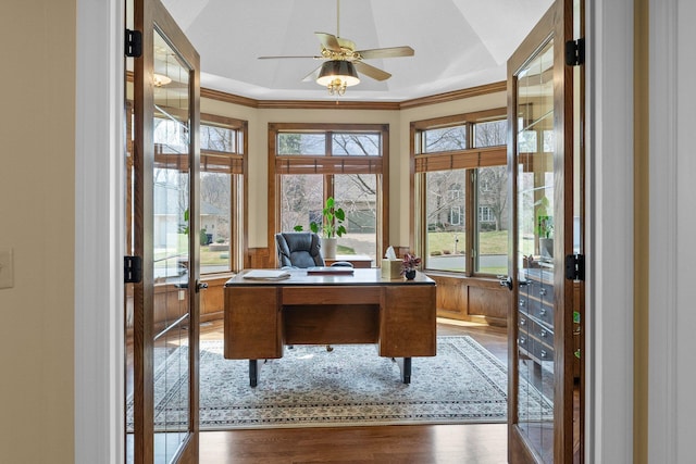 office space with wainscoting, a ceiling fan, ornamental molding, and wood finished floors