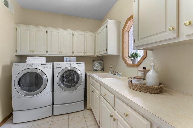 washroom featuring visible vents, washing machine and clothes dryer, cabinet space, light tile patterned floors, and a sink