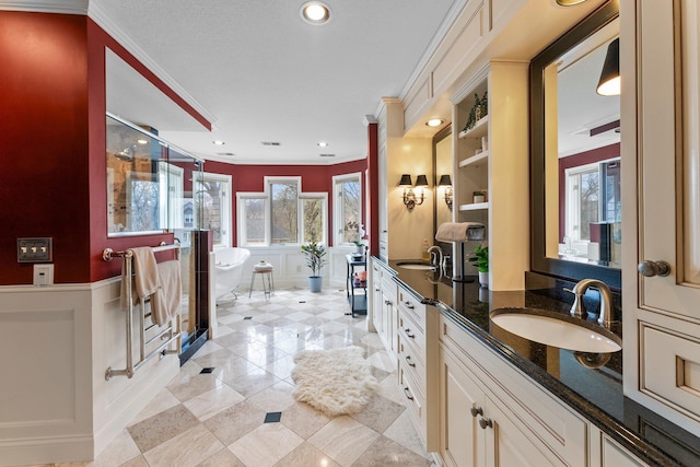 bathroom with double vanity, ornamental molding, a freestanding bath, a sink, and a stall shower