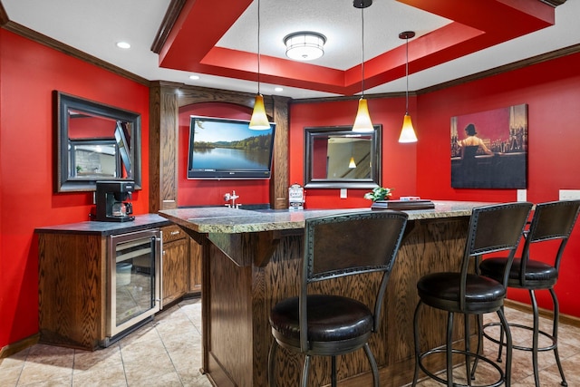 bar with ornamental molding, wine cooler, a raised ceiling, wet bar, and hanging light fixtures
