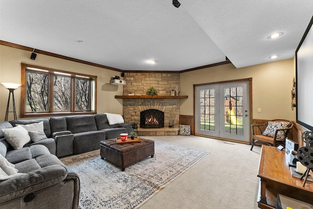 living area featuring crown molding, carpet, wainscoting, and a stone fireplace