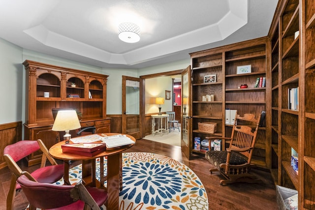 living area with wainscoting, wood finished floors, and a tray ceiling