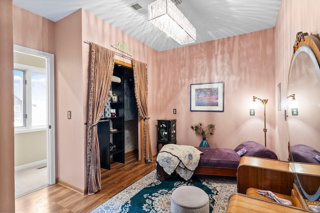 living area featuring an inviting chandelier, baseboards, wood finished floors, and visible vents