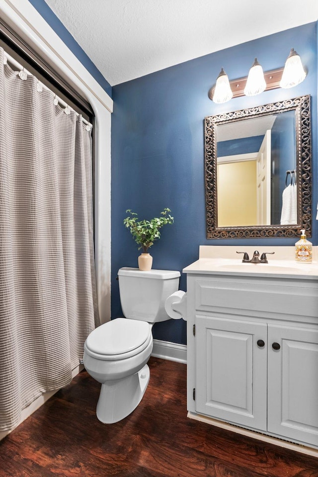 full bathroom with a textured ceiling, wood finished floors, baseboards, vanity, and toilet