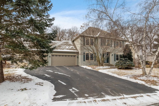 colonial-style house with an attached garage and aphalt driveway