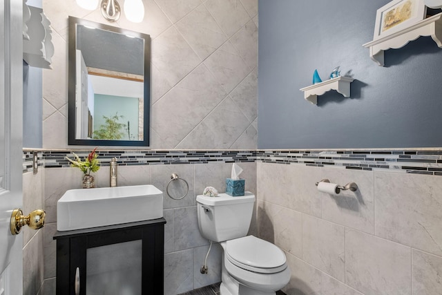 bathroom featuring toilet, vanity, and tile walls