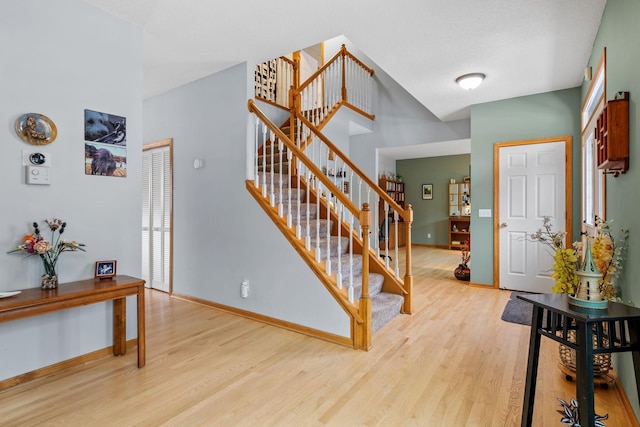 entryway with baseboards, wood finished floors, and stairs