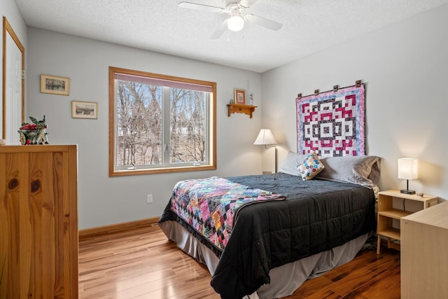 bedroom with baseboards, a ceiling fan, wood finished floors, and a textured ceiling