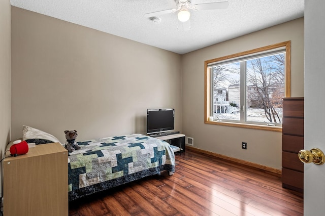 bedroom with a ceiling fan, wood finished floors, a textured ceiling, baseboards, and visible vents