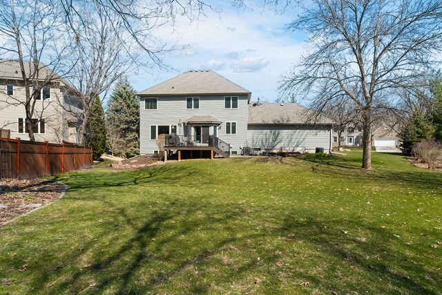 back of house with a lawn, a wooden deck, and fence