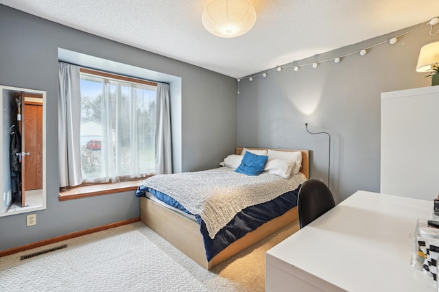 bedroom with a textured ceiling, baseboards, visible vents, and carpet