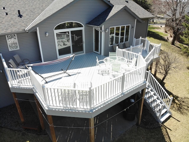 back of property featuring outdoor dining area, a shingled roof, stairs, and a deck