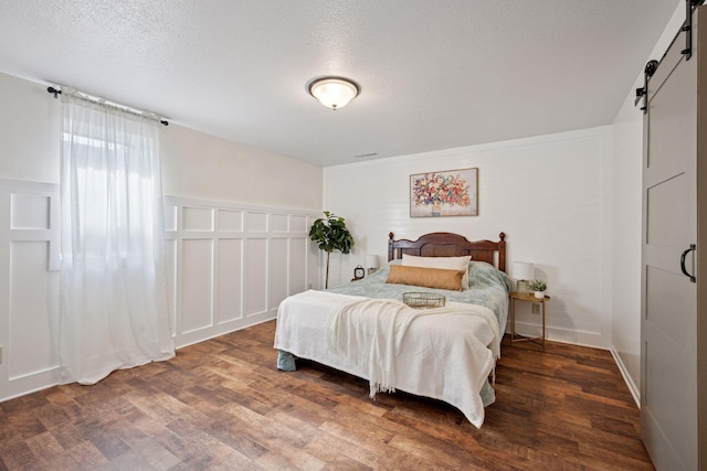 11 6th Ave S, Sartell, MN 56377 - bedroom featuring a barn door, wood finished floors, a textured ceiling, a decorative wall, and a closet