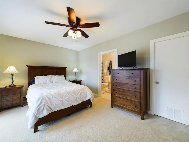 bedroom with ceiling fan, visible vents, light carpet, and ensuite bathroom