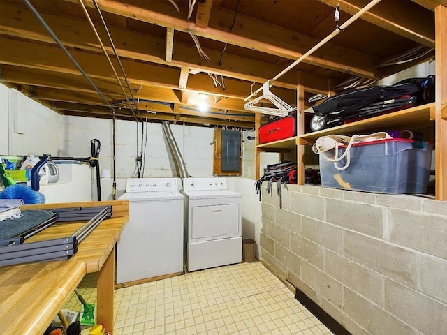 laundry room with concrete block wall, laundry area, washing machine and dryer, and electric panel