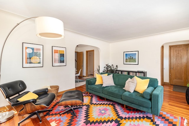 living room featuring arched walkways, wood finished floors, and baseboards